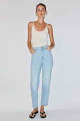 Pantalón jeans Z1975 de tiro alto y diseño mom fit, color azul claro con lavado desgastado, de corte tobillero y cinco bolsillos. Cierre frontal con cremallera y botón metálico.