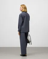 Camisa de manga larga color gris oscuro, confeccionada en algodón orgánico. Presenta un cuello alto con cierre de dos botones y un cinturón fino ajustable a la cintura.