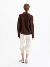 Pantalon negro de corte tipo babucha, con cintura estructurada, presillas para cinturón, bolsillos traseros y ruedos ajustados con puños tejidos.