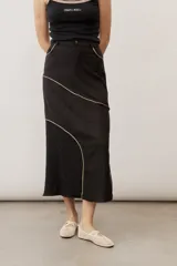 Pollera midi de corte recto, color negro, con costuras curvas decorativas en tono tostado y un panel lateral de encaje.