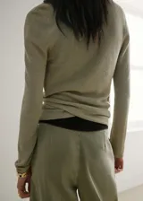 Cardigan cruzado de punto fino en color verde militar, con cuello en V, manga larga y cierre de lazo lateral.