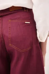 Pantalón de tiro alto, pierna ancha y largo, color beige claro con finas rayas verticales en tono oscuro. Presenta un diseño de cinco bolsillos estilo jean.
