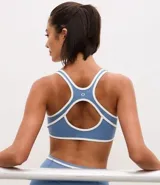Top deportivo de microfibra con diseño de espalda nadador, escote redondo y bies en color blanco a modo de contraste. Cuenta con copas desmontables para mayor soporte y ajuste.