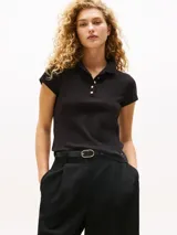 Chomba de algodón elástico color negro, de corte slim fit, con cuello de chomba y cartera de cinco botones dorados. Presenta logo de Tommy Hilfiger bordado en el bajo.