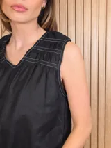 Musculosa de lino color blanco, de corte holgado, con cuello en V, detalles de tablas y frunces en los hombros, y dobladillo desflecado.