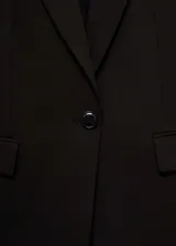 Blazer entallado de color negro con cuello de solapa con muesca, hombros estructurados y cierre frontal de un botón. Presenta diseño recto, manga larga, dos bolsillos de ribete delanteros y abertura posterior.