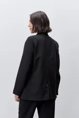 Blazer sastrero negro de silueta recta y calce relajado, con cuello con solapas, hombros levemente estructurados y bolsillos delanteros con vivo.