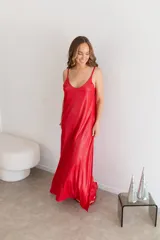 Vestido largo rojo brillante, con escote en V y tirantes finos. Presenta un corte holgado y abertura lateral en la falda.