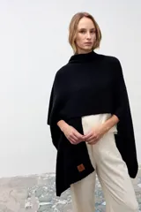 Chal de tejido de punto texturizado en color negro, con diseño envolvente y etiqueta de cuero sintético con logo en el extremo inferior.