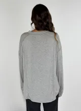 Remera negra de corte holgado con cuello redondo y botones en el frente. Presenta costuras a la vista en color blanco.