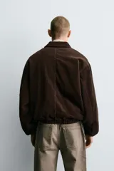 Cazadora de corte cropped confeccionada en pana de algodón con interior acolchado. Presenta cuello solapa, cierre frontal de cremallera, bolsillos frontales tipo canguro y acabados con elástico en puños y bajo.