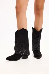 Bota de caña media en color beige, confeccionada en gamuza con diseño slouchy. Presenta una caña decorada con múltiples tachas metálicas pequeñas y un taco cuadrado de altura media.