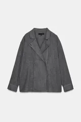 Camisa de corte oversize confeccionada en algodón, con estampado de cuadros pequeños en tonos grises. Presenta cuello solapa, cierre frontal con botones ocultos y mangas largas con puños rectos.