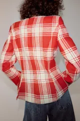 Chaqueta entallada de Zara Woman Collection confeccionada en mezcla de algodón con diseño de cuadros en tonos rojo y crudo. Presenta escote en pico, manga larga, bolsillos de vivo en el delantero y bajo asimétrico con cierre frontal de ganchos metálicos.