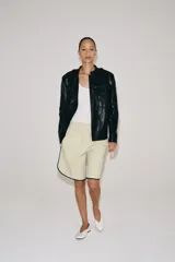 Cazadora efecto piel de Zara Woman Collection, en color negro. Cuenta con cuello redondo, manga larga, bolsillos de parche con solapa en el delantero y cierre frontal con botones forrados. Incluye un cinturón del mismo tejido para ajustar en la cintura.
