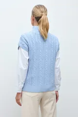 Chaleco de tejido de punto color crudo, con diseño de ochos verticales y cuello redondo. Presenta un corte holgado y terminaciones acanaladas en cuello, sisas y ruedo.