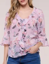 Blusa de gasa rosada con estampado floral, escote en V con volados en cascada en la pechera y mangas tres cuartos acampanadas.
