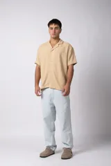 Camisa de manga corta color negro, con cuello cubano y botones frontales. Tejido de lino con textura entramada.