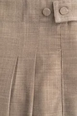 Pantalón sastrero de corte amplio y tiro alto, color beige/tostado con textura sarga. Presenta pinzas frontales y pliegues marcados en las piernas. Tiene cierre con botón y corchete ocultos, y detalles de ajuste con botones forrados en la cintura trasera.