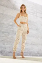 Pantalón largo color arena con estampado floral, tiro alto, bolsillos laterales y tobillos ajustados con lazos.