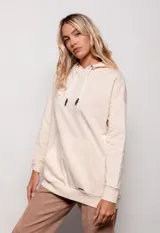 Canguro oversize color beige, de tela deportiva, con capucha ajustable con cordones y bolsillo tipo canguro en el frente.