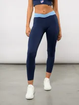 Calza deportiva larga de color azul marino con pretina cruzada en contraste color celeste. Diseño ajustado al cuerpo con cintura alta, ideal para actividades físicas.