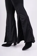 Calza negra de tiro alto, corte ajustado en la parte superior y acampanado en la parte inferior, con aberturas laterales en el ruedo.