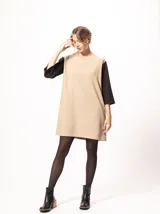 Vestido corto negro con mangas 3/4 verdes, cuello bote y bolsillos laterales.