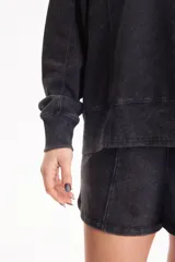 Buzo deportivo sin frisa de color negro con efecto lavado, cuello redondo, mangas largas y estampa frontal con texto en blanco.