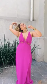 Vestido largo de crepé con acabado metalizado, escote en V profundo con detalle de aro central, aberturas laterales en la cintura y falda con tajo frontal.