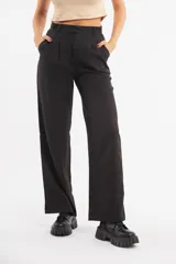 Pantalón de vestir negro, tiro alto, de corte ancho y recto, con pinzas frontales.