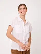 Camisa de manga corta color blanco, confeccionada en mezcla de algodón y lino, con cuello camisero, cierre frontal de botones y dos bolsillos plaqué en el pecho.