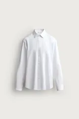 Camisa slim fit de Zara confeccionada en tejido de algodón con textura estructurada, cuello clásico con solapa y manga larga con puños abotonados. Cierre frontal con botonadura.