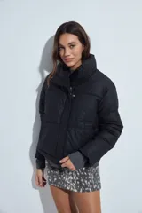 Campera puffer de nylon color marrón oscuro, con cuello alto, cierre frontal y puños elásticos. Diseño acolchado de volumen ligero.