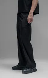 Pantalón cargo de corte oversize confeccionado en microfibra técnica con sutil elasticidad. Presenta cintura elástica, bolsillos laterales y un bolsillo cargo con cierre de broche snap. Incluye un sistema de elásticos con tancas en los tobillos para regular la apertura y la silueta.