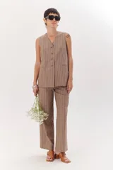 Chaleco largo color blanco con rayas verticales finas color beige, con cuello en V y cierre frontal con botones marrones. Incluye pañuelo al cuello con estampado de lunares y rayas.