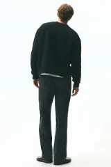 Cárdigan negro de punto peludo suave, con cuello en V pronunciado y cierre frontal de botones. Presenta remates acanalados en puños y bajo.