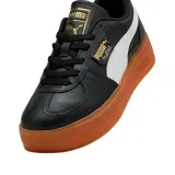 Championes urbanos Puma modelo Palermo Platform, color negro con franja lateral blanca y suela de plataforma color caramelo. Presenta detalles en dorado en la lengüeta y el lateral.