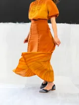 Falda larga color ocre con teñido degradado horizontal en tonos anaranjados. Confeccionada en algodón tipo seda, corte a la cintura, bolsillos laterales y cierre invisible.