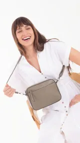 Bandolera color bordó con diseño texturizado geométrico en el frente, bolsillo frontal con cierre, bolsillo trasero con cierre y compartimento principal con divisiones. Incluye correa extensible.