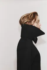 Chaqueta entallada de tejido efecto neopreno en color negro, con cuello solapa amplio, cierre frontal con cremallera y mangas largas abullonadas.