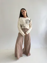 Sweater de punto color marrón chocolate con diseño floral bordado en cordón color crudo. Presenta cuello redondo, mangas largas y puños acanalados.