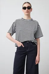 Remera de manga corta con cuello a la base, confeccionada en tejido de rayas horizontales blancas y negras, con silueta relajada.