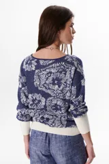 Sweater de tejido de punto con diseño floral, confeccionado en una mezcla de algodón y lurex. Presenta cuello redondo, mangas largas con puños anchos en color crema y un calce holgado.
