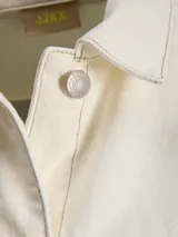Chaqueta de denim en color crudo, con cierre frontal de botones metálicos, bolsillos frontales aplicados y cuello camisero.