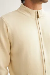 Campera tejida color marrón claro con cierre delantero, cuello alto y bolsillos delanteros. Tejida en 100% lana fina sin teñir.