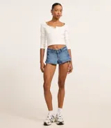 Short de jean azul con cierre frontal, trabillas en la cintura y detalle de cordones entrelazados en los laterales. Presenta un corte ajustado y acabado clásico.