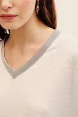 Remera de lino y viscosa color blanco, de corte holgado, manga corta y escote en V con detalle de aplicación brillante.
