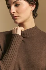 Polera de cuello alto confeccionada en tejido de punto negro, con diseño de textura acanalada en cuello, puños y ruedo, y trama vertical en mangas y espalda.