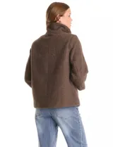 Tapado de tejido bouclé color marrón, con silueta evasé y largo a la cadera. Presenta cuello alto envolvente, cierre frontal oculto con botones a presión y bolsillos frontales de gran tamaño. Sus mangas son 3/4 con corte amplio y puños de tejido rib al tono que se extienden para cubrir las muñecas.